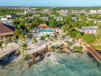 Kompleks hotelowy z basenem, palmami i pomostami nad brzegiem z czystą wodą