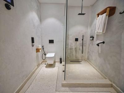 Nowoczesna łazienka z prysznicem bezbrodzikowym, wiszącą toaletą i minimalistycznym designem.