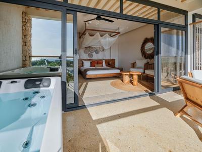 Nowoczesny balkon hotelowy z jacuzzi prowadzący do pokoju z łóżkiem z baldachimem i rustykalnym wystrojem.