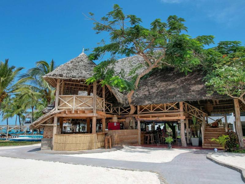 Casa sulla spiaggia tradizionale in legno con tetti di foglie di palma in una località tropicale.