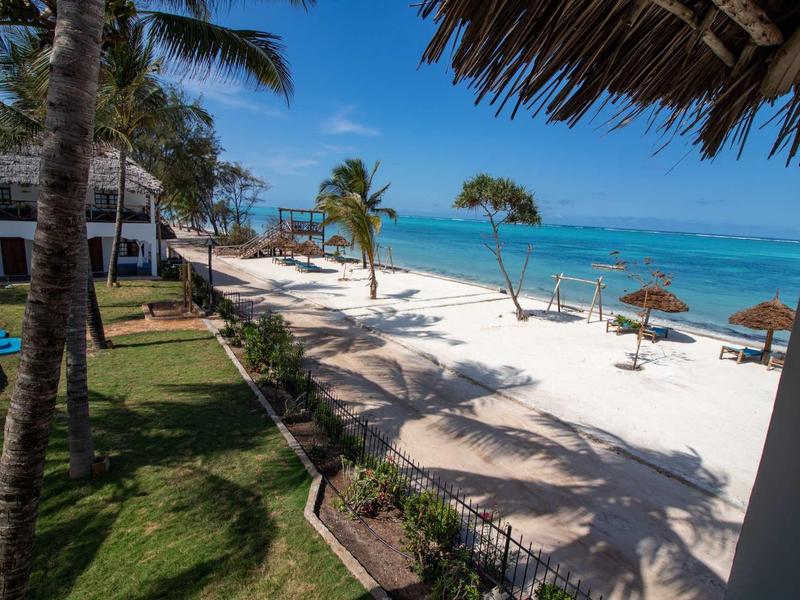 Spiaggia tropicale con sabbia bianca, palme e lettini in un resort alberghiero.