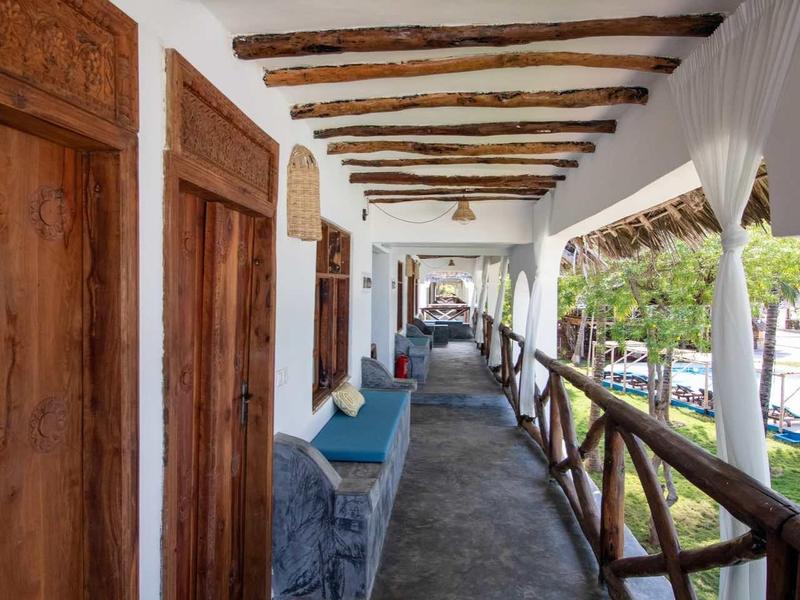 Corridoio rustico dell'hotel con travi di legno, porte in legno e panchina lungo il corridoio.