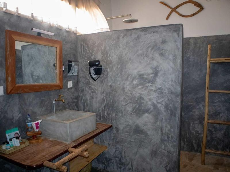 Bagno moderno con lavabo in cemento, mobili in legno e mensola scala rustica.
