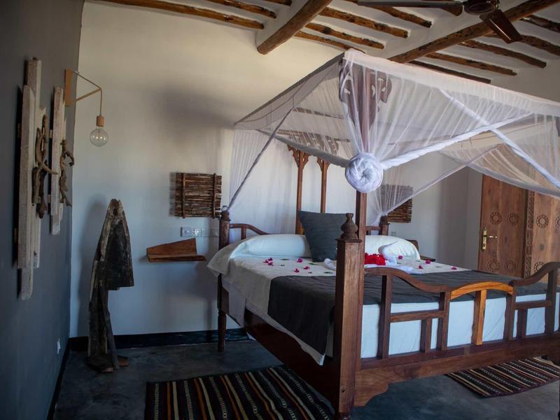 Camera rustica con letto a baldacchino, zanzariera e mobili in legno in un ambiente accogliente.