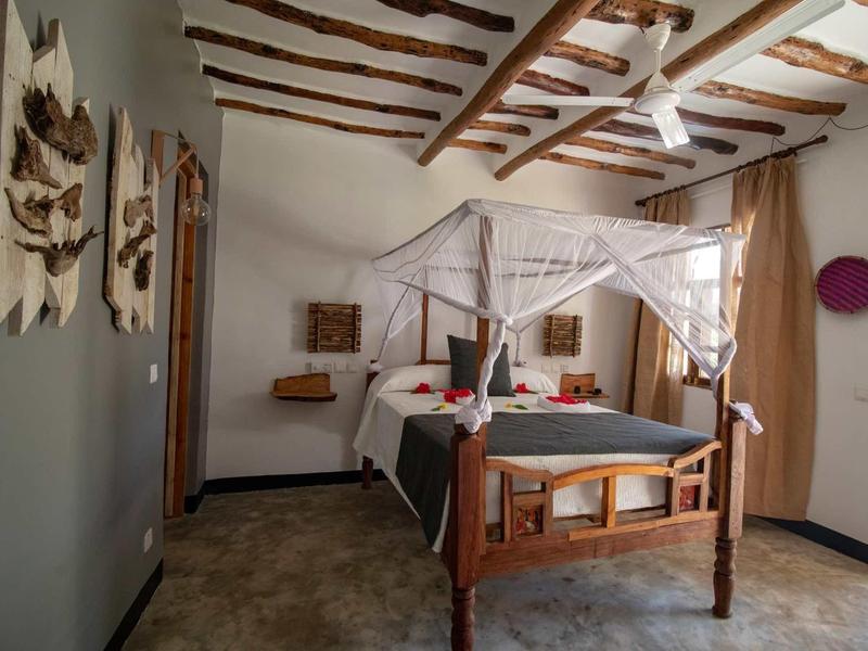 Camera rustica con struttura del letto in legno e travi a vista in una stanza d'albergo.