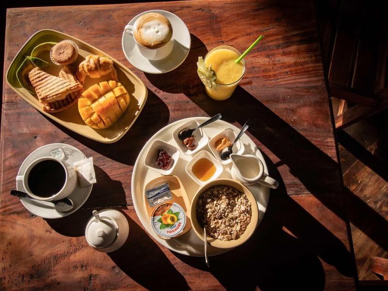 Varie pietanze della colazione e bevande su un tavolo di legno in hotel.