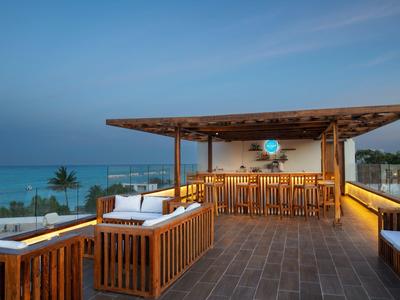 Terrazza panoramica con bar in legno e vista mare al tramonto.