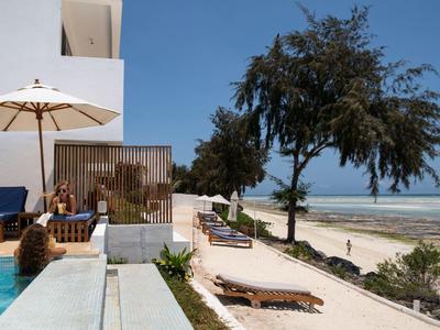 Hotel sulla spiaggia con lettini, ombrellone e vista mare sotto un cielo sereno.
