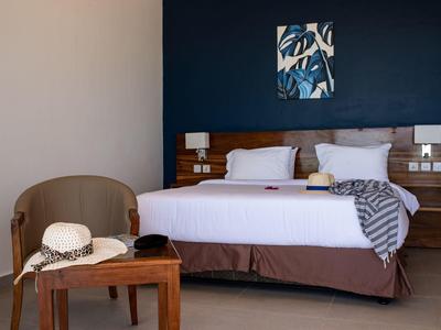 Camera d'hotel accogliente con letto matrimoniale, sedia, tavolo di legno e decorazione murale moderna.