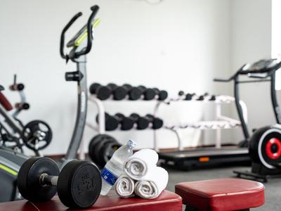 Salle de sport avec haltères, serviettes, vélo stationnaire et tapis roulant dans un hôtel.