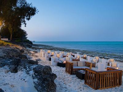 Spiaggia con comodi posti a sedere e tavoli vicino al mare al crepuscolo.