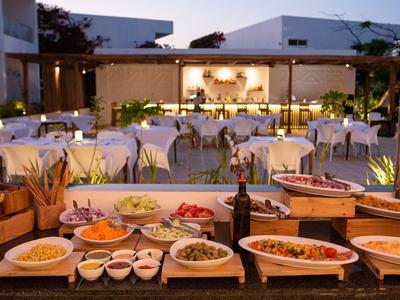 Buffet extérieur élégant avec divers plats et tables dressées dans un jardin d'hôtel.