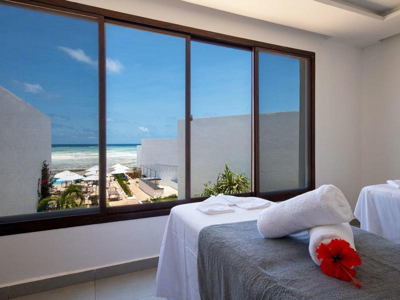 Sala massaggi luminosa con vista sul mare attraverso grandi finestre.