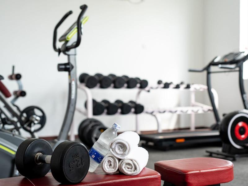 Palestra con manubri, ellittica, tapis roulant e asciugamani arrotolati.