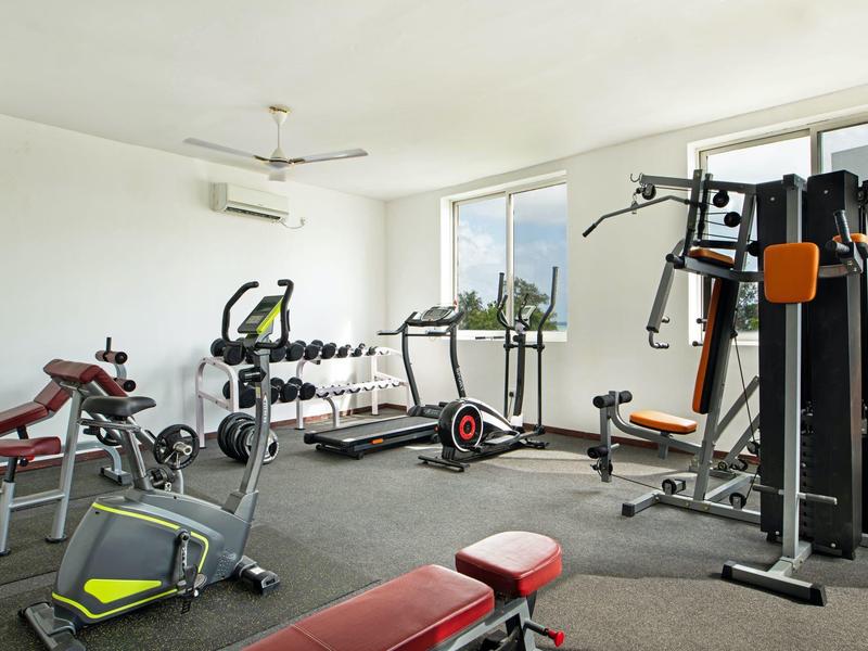 Palestra luminosa con attrezzature moderne e grandi finestre con vista sul verde.