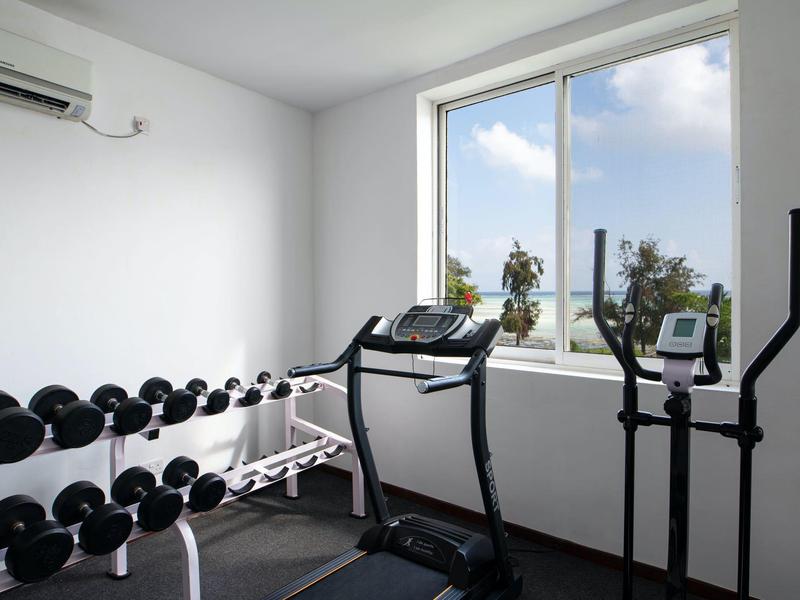 Palestra piccola con manubri, tapis roulant e ellittica davanti a una grande finestra.