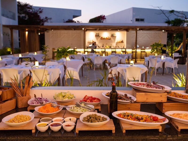 Buffet con vari piatti e bevande davanti a un ristorante aperto di notte.