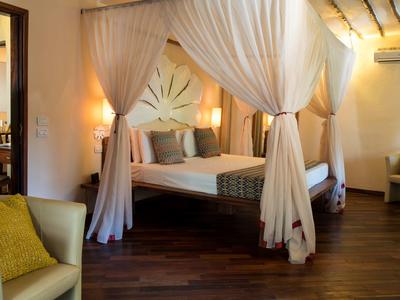 Schlafzimmer mit Holzlattenbett, weißen Vorhängen, Holzboden und gemütlicher Beleuchtung.