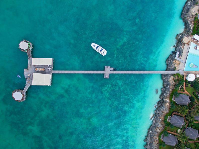 Vue aérienne d'une jetée s'étendant sur une eau turquoise claire jusqu'à une petite plateforme.
