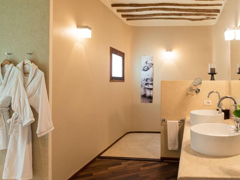 Salle de bain moderne avec deux lavabos, serviettes et peignoirs accrochés au mur.