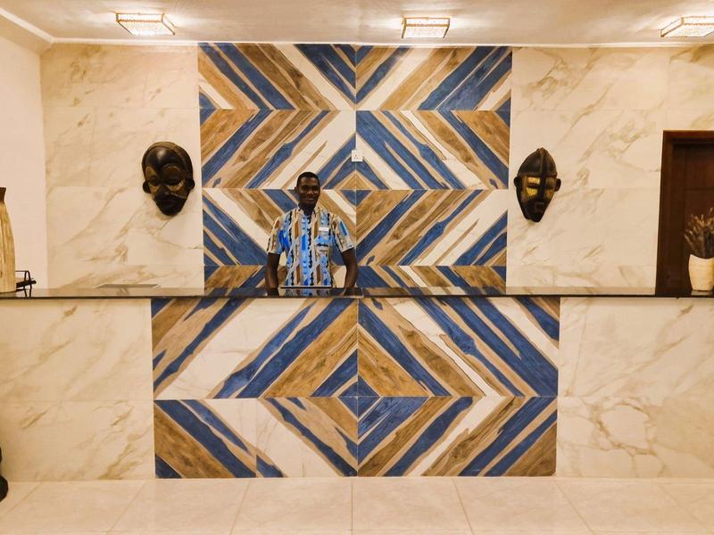 Empfangstresen mit buntem Mosaik, darunter Marmor, mit afrikanischen Masken und Holzdekor an Wänden.