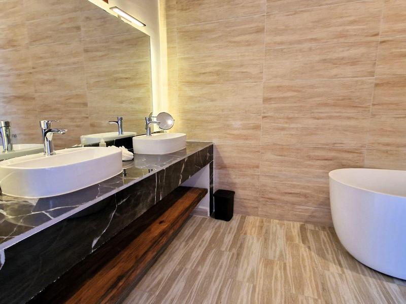 Modernes Badezimmer mit runder Badewanne, zwei weißen Rundbecken und schwarzer Steinplatte.