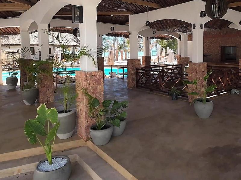 Offener Raum mit Pools, Holzdecke, Steinwänden und zahlreichen Pflanzen in Töpfen.