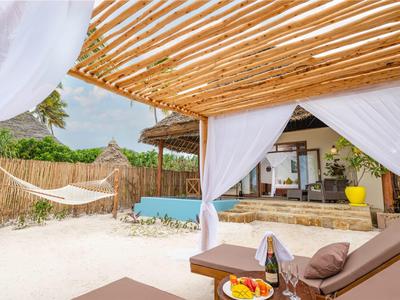 Gemütliche Strandlounge mit Holzdach, weißen Vorhängen, Hängematte und kleinem Pool.