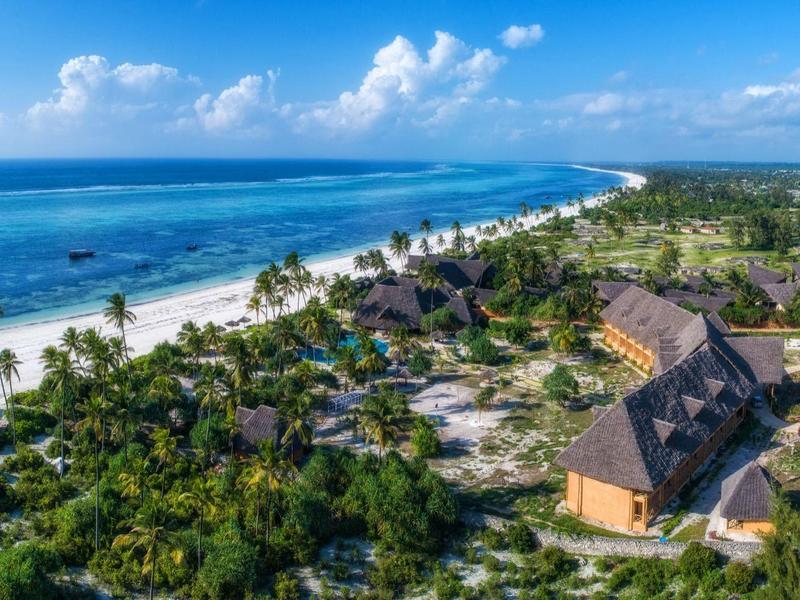 Luftaufnahme eines tropischen Strandes mit weißem Sand, türkisfarbenem Meer und grüner Vegetation.