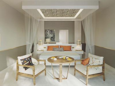 Nowoczesny pokój hotelowy z podwójnym łóżkiem, dwoma fotelami i okrągłym stołem w neutralnych kolorach.