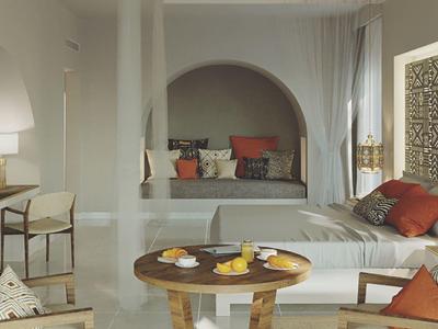 Przytulna część wypoczynkowa i sypialna z drewnianym stołem i dywanem w nowoczesnym pokoju hotelowym.