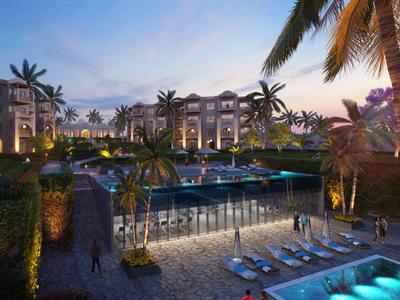 Luksusowy ośrodek o zmierzchu z oświetlonym basenem i leżakami, otoczony palmami.