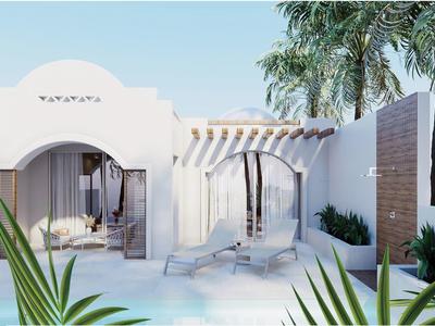 Biały budynek z oknami w kształcie łuku, taras z leżakami i palmami na pierwszym planie.