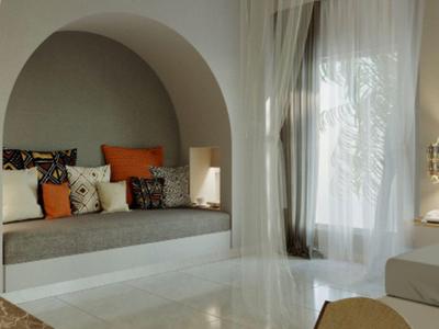 Jasny salon hotelowy z przytulnym miejscem do siedzenia, poduszkami i zasłonami sięgającymi podłogi.