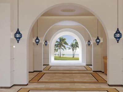 Spacious bright hotel corridor with arches and view of palm trees and sea