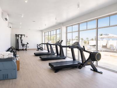 Nowoczesna siłownia z bieżniami i dużym oknem z widokiem na taras na zewnątrz.