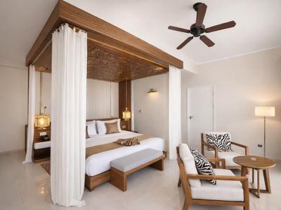 Nowoczesna sypialnia z łóżkiem z baldachimem, jasnymi drewnianymi meblami i wentylatorem sufitowym.