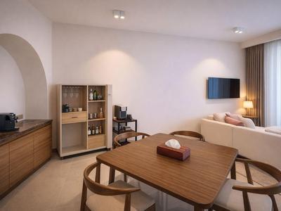 Nowoczesny salon z jadalnią, sofą, telewizorem i aneksem kuchennym w ciepłych kolorach.