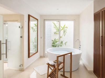 Nowoczesna łazienka z wolnostojącą wanną, drewnianymi meblami i dużymi oknami z widokiem na rośliny.