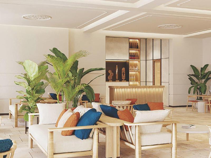 Jasny, nowoczesny hol hotelowy z przytulnymi miejscami do siedzenia i dużymi roślinami doniczkowymi.