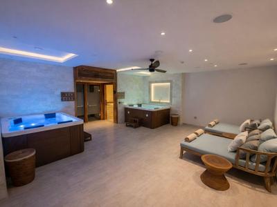 Moderner Wellnessraum mit Whirlpool, Sauna, Sitzbank und entspannender Beleuchtung.