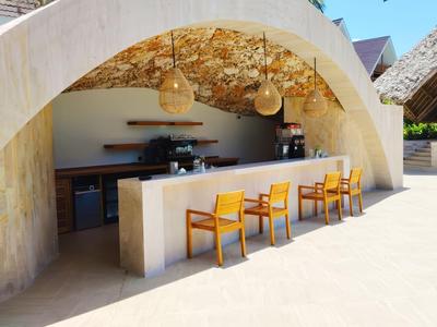 Moderner Außenbarbereich mit Stühlen unter einem Bogen und dekorativem Blattwerk an der Decke.