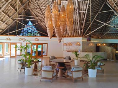 Großer, offener Lounge-Bereich mit Holzdecke, Pflanzen und Sitzgelegenheiten in einem Hotel.