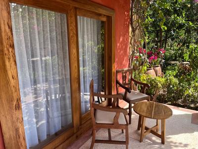 Terrazza con sedie in legno e un piccolo tavolo davanti a una finestra con tende bianche