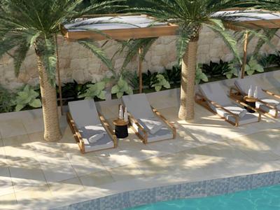 Area piscina con sedie a sdraio e ombrelloni, circondata da palme e natura.