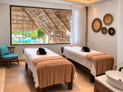 Hotelzimmer mit zwei Betten, blick auf Pool und tropische Umgebung durch Fenster.