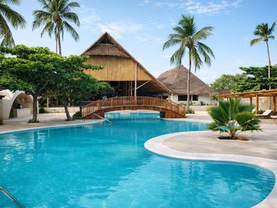 Runder Swimmingpool mit Brücke und Palmen in tropischem Hotelresort.