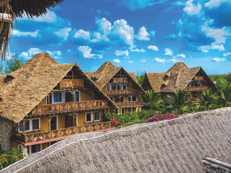 Traditionelle strohgedeckte Häuser unter einem blauen Himmel mit weißen Wolken.