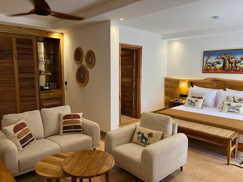 Wohnzimmer mit zwei beigen Sesseln, Holz-Couchtisch, Sofa, Holzfenstern und warmem Licht.