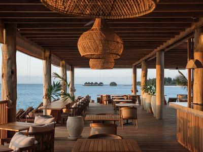 Area terrazza aperta con soffitto in legno e luci a cesto, vista sul mare.